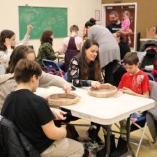 A room full of grade 5 students and staff working on making their hand drum