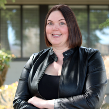 Woman with short brown hair wearing black leather jacket poses for photo