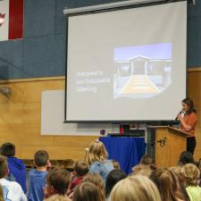 Female principal stands in front of school assembly