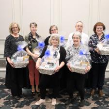 Employees stand for group photo holding white gift boxes received for their years of service