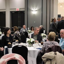 Attendees sitting at tables or standing and mingling