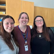 Three female support staff smile for photo